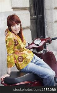 Portrait of a young woman sitting on a motor scooter