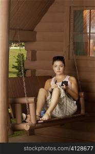 Portrait of a young woman sitting on a swing and holding a makeup brush
