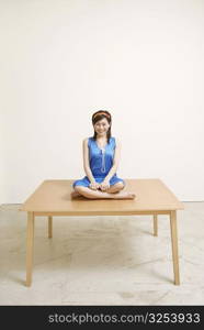 Portrait of a young woman sitting on a table and smiling