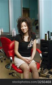 Portrait of a young woman sitting on an armchair in a hair salon
