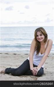 Portrait of a young woman sitting on the beach and smiling