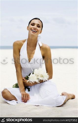 Portrait of a young woman sitting on the beach and smiling