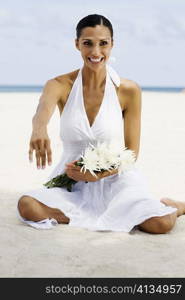 Portrait of a young woman sitting on the beach and smiling