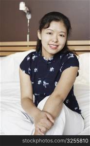 Portrait of a young woman sitting on the bed smiling