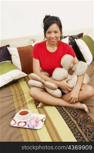 Portrait of a young woman sitting on the bed with cushions and smiling