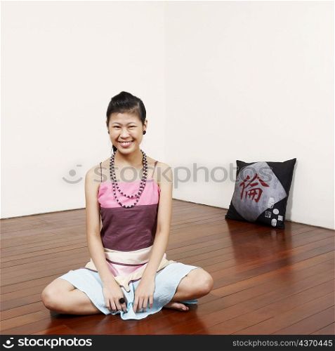 Portrait of a young woman sitting on the floor and smiling