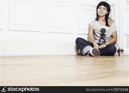 Portrait of a young woman sitting on the floor at the corner of a room