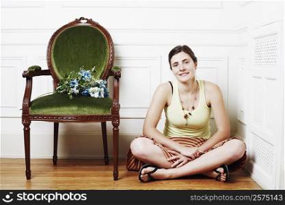 Portrait of a young woman sitting on the floor near an armchair