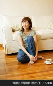 Portrait of a young woman sitting on the floor with a cup of tea beside her