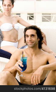 Portrait of a young woman sitting with a mid adult man holding a cocktail