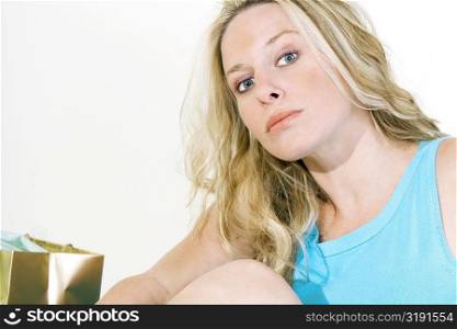 Portrait of a young woman sitting with a shopping bag