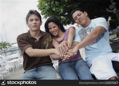 Portrait of a young woman sitting with two young men and smiling