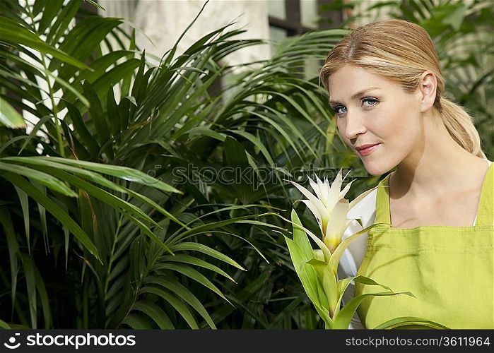 Portrait of a young woman smelling flower in garden center