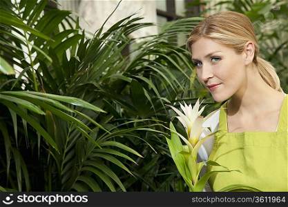 Portrait of a young woman smelling flower in garden center