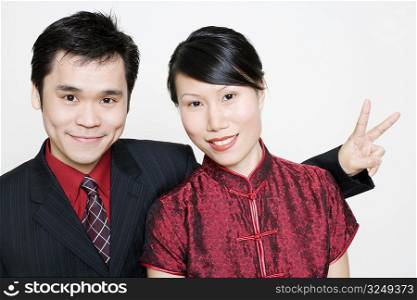 Portrait of a young woman smiling and a mid adult man making a peace sign