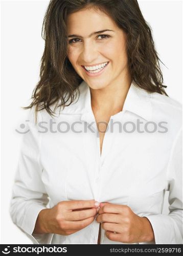 Portrait of a young woman smiling and buttoning her shirt