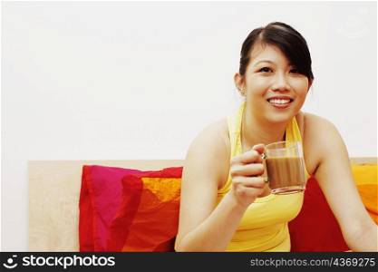 Portrait of a young woman smiling and holding a cup of coffee