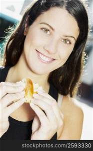 Portrait of a young woman smiling and holding bread