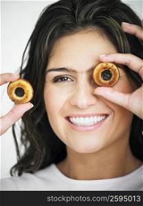 Portrait of a young woman smiling and holding two hollow cookies