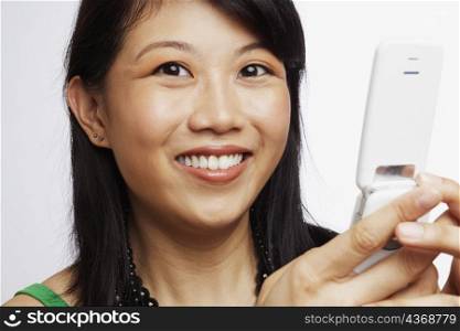 Portrait of a young woman smiling and operating a mobile phone