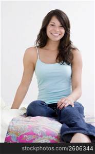 Portrait of a young woman smiling and sitting on the bed