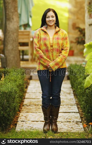 Portrait of a young woman smiling and standing with her hands clasped