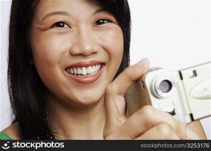 Portrait of a young woman smiling and taking a photograph