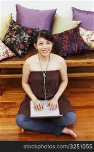 Portrait of a young woman smiling and using a laptop