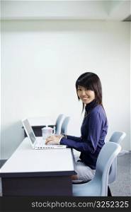 Portrait of a young woman smiling and using a laptop