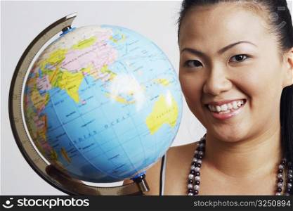Portrait of a young woman smiling beside a globe