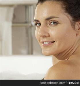 Portrait of a young woman smiling in a bathtub