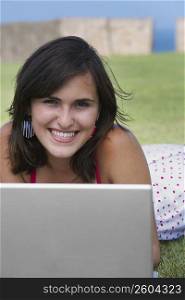 Portrait of a young woman smiling in front of a laptop