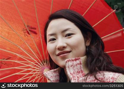 Portrait of a young woman smiling under a parasol