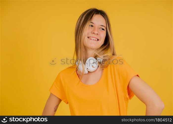 Portrait of a young woman smiling while posing with headphones against isolated background.
