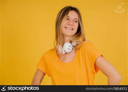 Portrait of a young woman smiling while posing with headphones against isolated background.