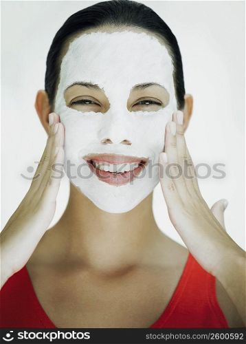 Portrait of a young woman smiling with a facial mask on her face