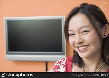 Portrait of a young woman smiling with a flat screen in the background