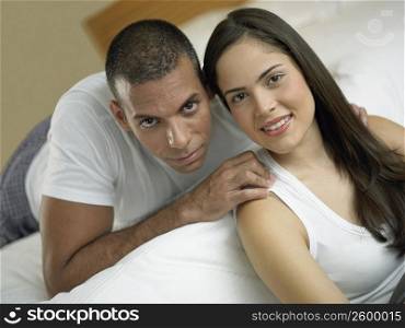 Portrait of a young woman smiling with a mid adult man lying on the bed