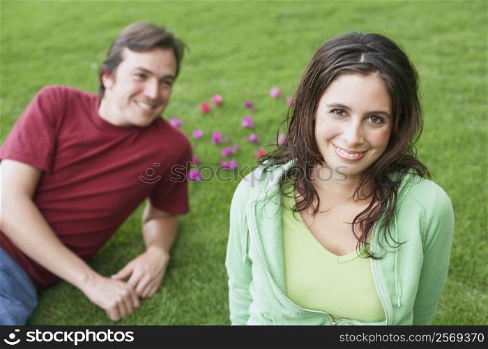 Portrait of a young woman smiling with a mid adult man lying on the grass