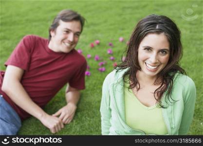 Portrait of a young woman smiling with a mid adult man lying on the grass