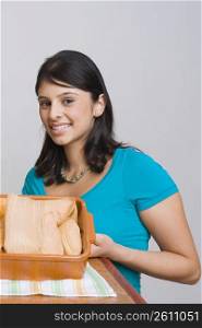 Portrait of a young woman smiling with a tray of breads in the kitchen
