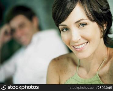 Portrait of a young woman smiling with a young man in the background