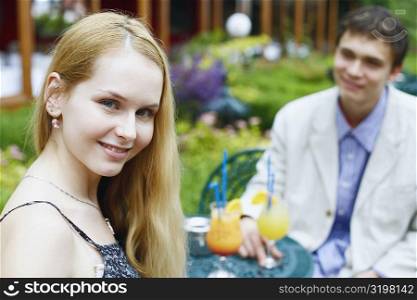Portrait of a young woman smiling with a young man sitting with her