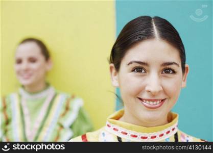 Portrait of a young woman smiling with another young woman standing in the background