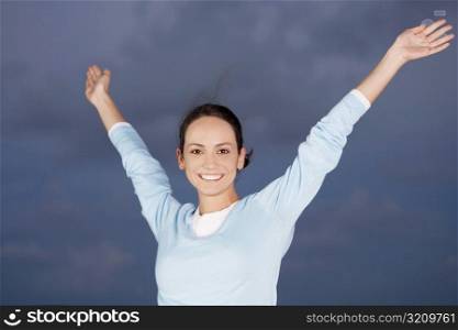 Portrait of a young woman smiling with her arms raised