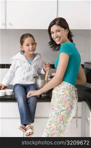 Portrait of a young woman smiling with her daughter in a kitchen