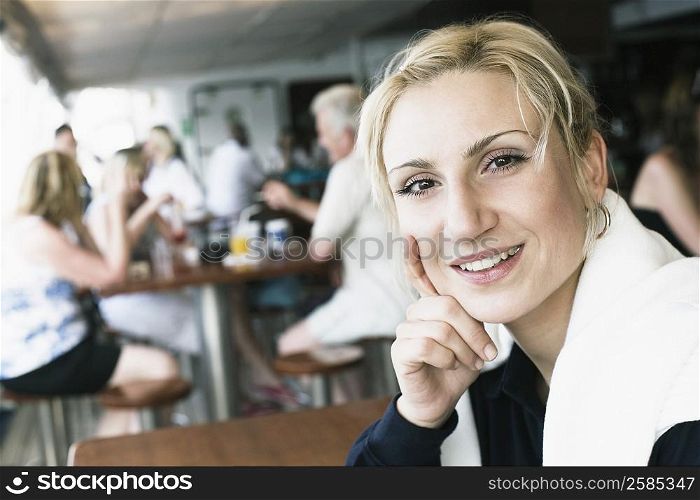 Portrait of a young woman smiling with her hand on her chin in a restaurant