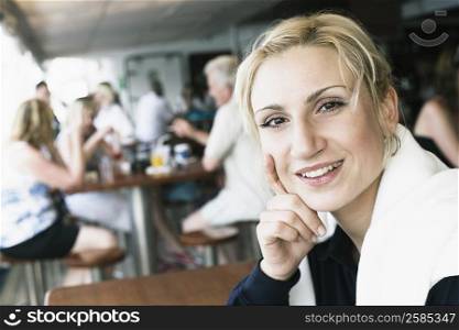 Portrait of a young woman smiling with her hand on her chin in a restaurant