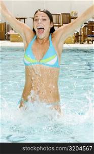 Portrait of a young woman splashing water in a swimming pool