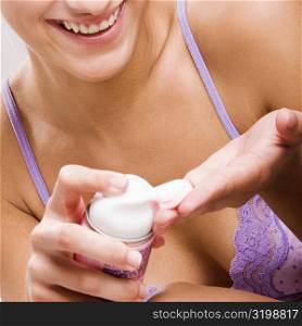 Portrait of a young woman squeezing shaving cream on her hand